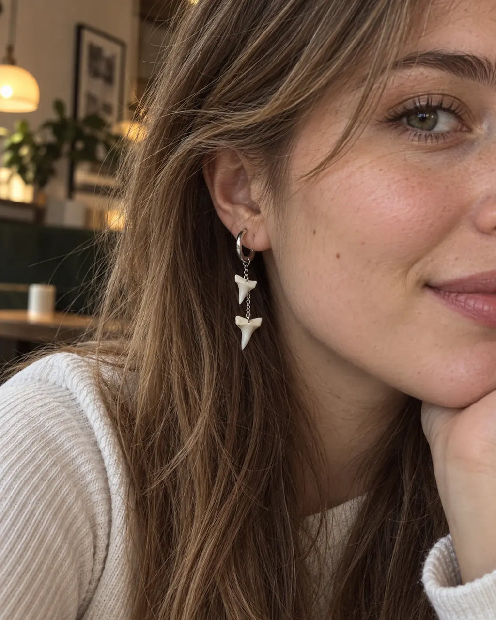 Two-tooth Abyss Fang shark tooth earring worn with loose brown hair and a white top