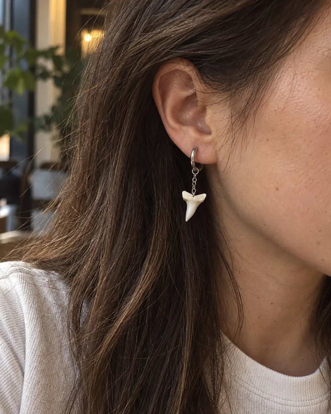 Close-up of a single-tooth Abyss Fang shark tooth earring showing its hoop and short chain
