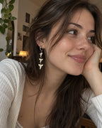 Three-tooth Abyss Fang shark tooth earring worn in a portrait with the cheek resting on one hand