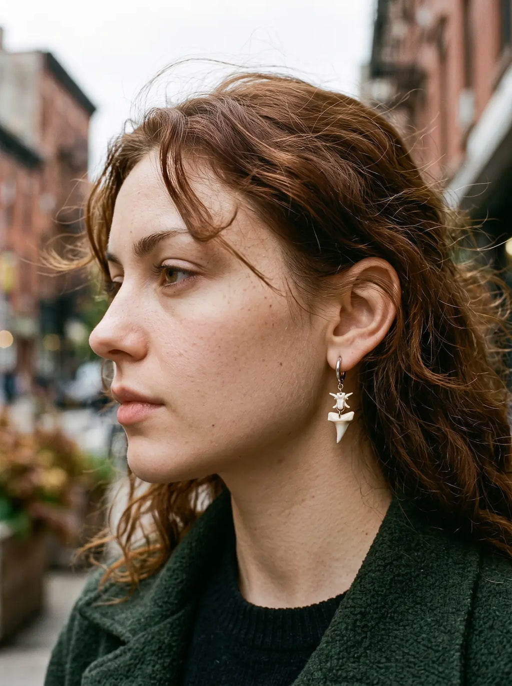 Abyssal mako shark tooth and snake bone earring worn outdoors in side profile
