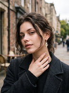 Abyssal mako shark tooth and snake bone earring worn with a dark coat and a hand at the collar