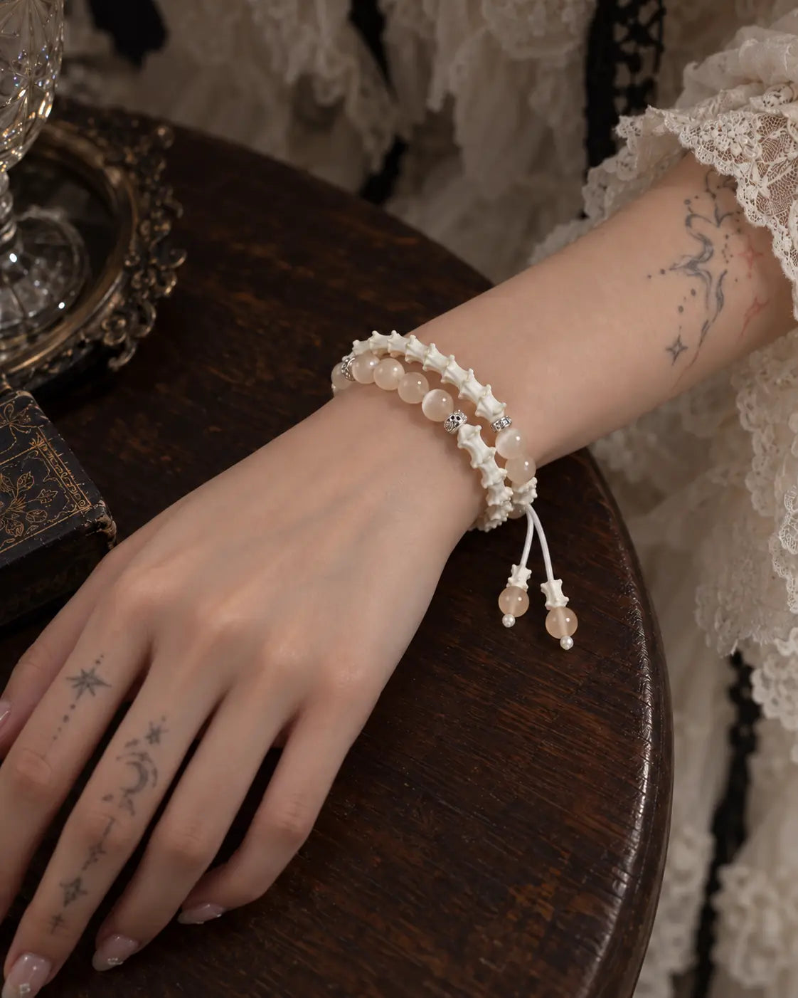 Apricot Glow snake bone bracelet worn in two rows on a wrist resting on a wooden table