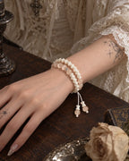 Angled close-up of the Apricot Glow snake bone bracelet and dangling cord ends over a wooden tabletop