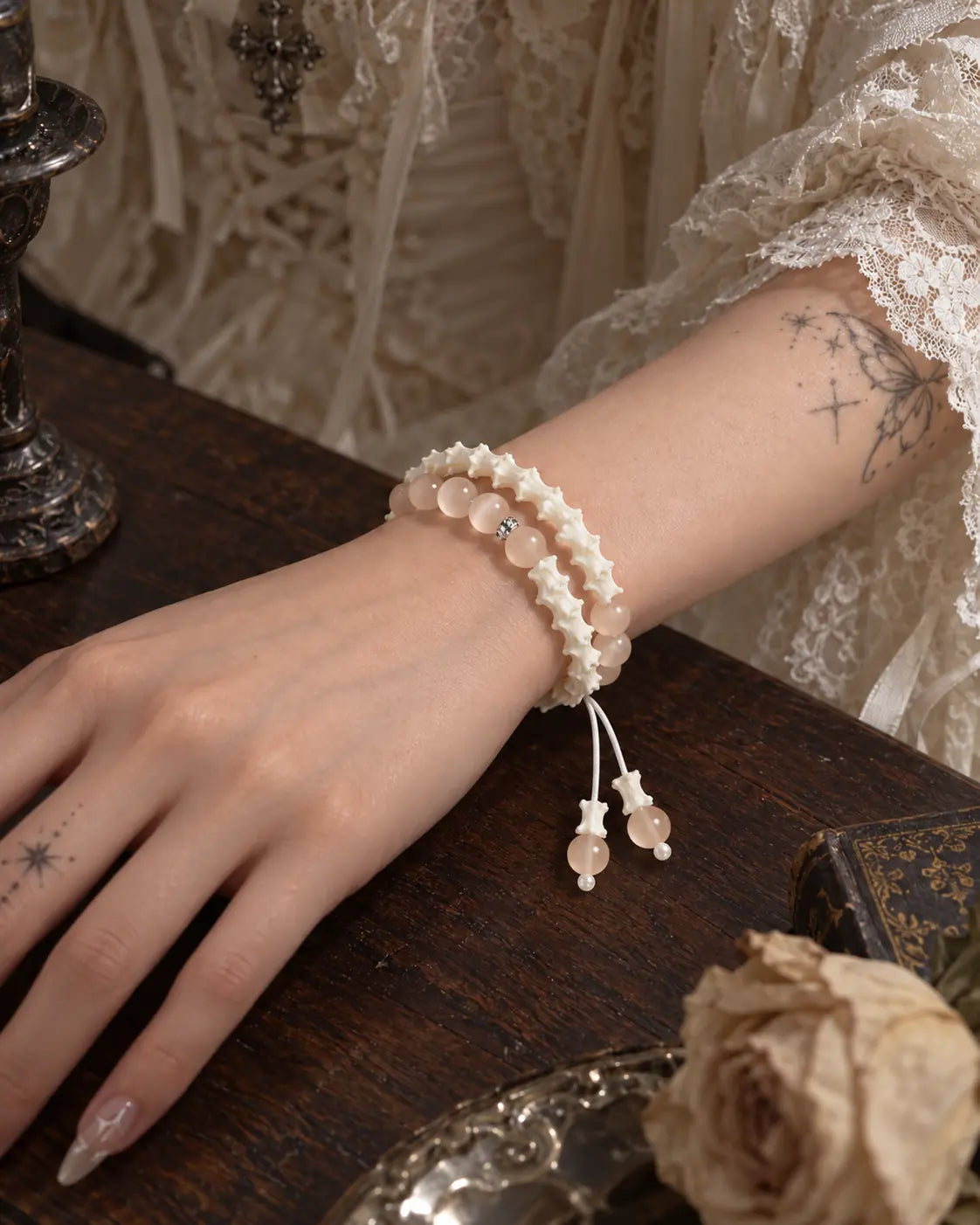 Angled close-up of the Apricot Glow snake bone bracelet and dangling cord ends over a wooden tabletop