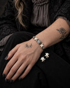 Ashen Leaf snake bone bracelet on a hand resting on the thigh, showing the gray bead and white vertebrae