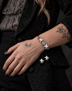 Ashen Leaf snake bone bracelet worn with the hand resting near the waist of a black patterned jacket