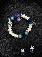 Azure Serpent Eye snake bone bracelet with blue beads, a silver-tone serpent and an iridescent eye charm on black fabric