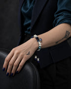 Azure Serpent Eye snake bone bracelet on a wrist resting over the curved back of a dark chair