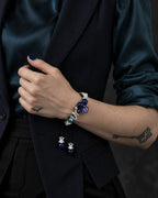 Azure Serpent Eye snake bone bracelet worn with the hand holding a dark vest lapel