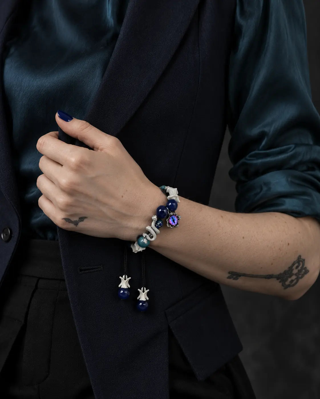 Azure Serpent Eye snake bone bracelet worn with the hand holding a dark vest lapel