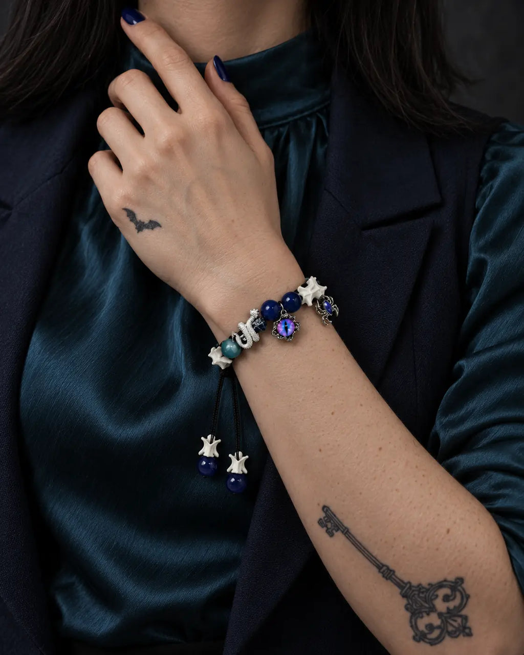 Azure Serpent Eye snake bone bracelet worn beside a blue velvet collar, showing its serpent and eye charm