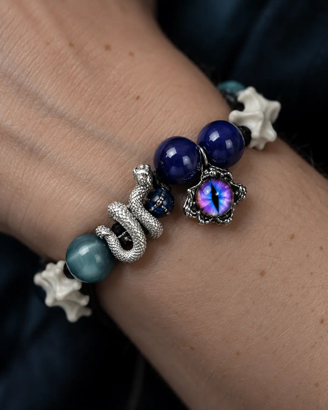 Close-up of the Azure Serpent Eye snake bone bracelet showing a silver-tone serpent, blue beads and an iridescent eye