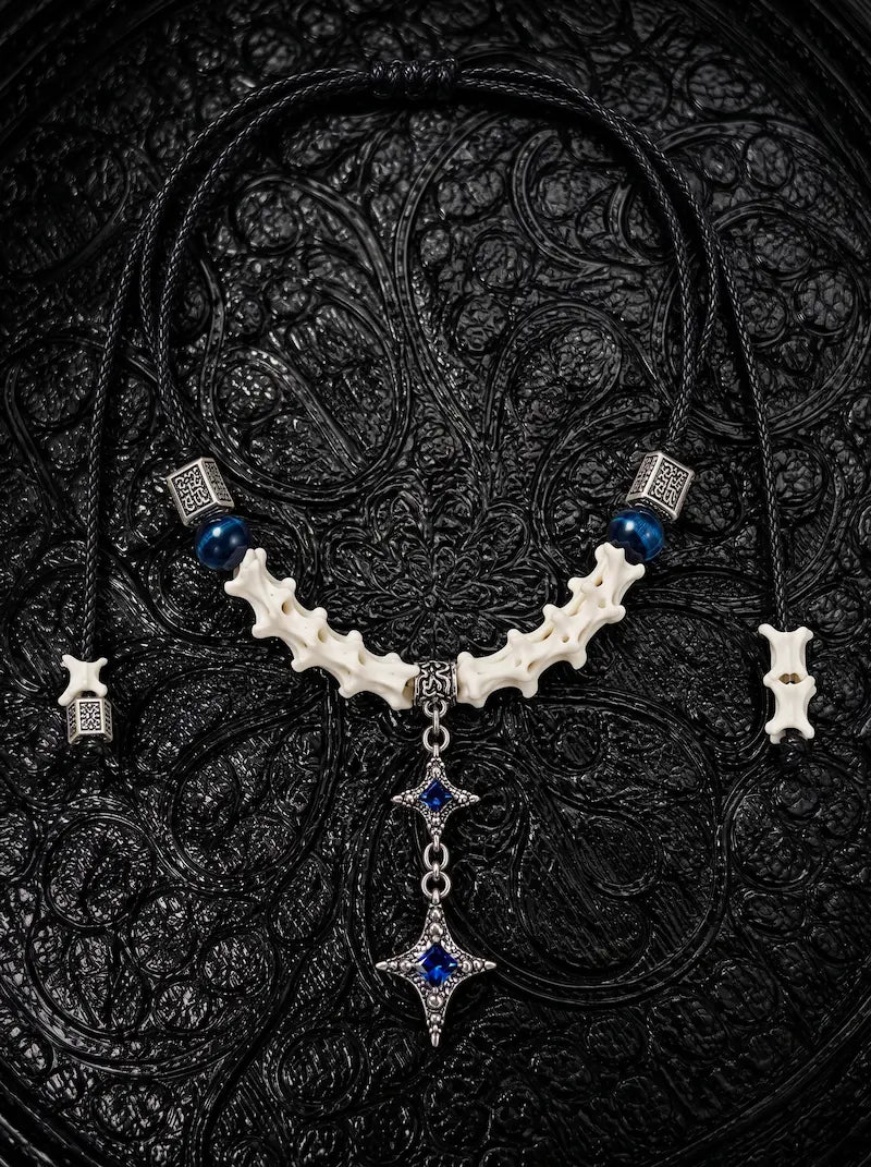 Azure Twin Star snake bone necklace with blue beads and two hanging silver-tone stars with blue centers on black fabric
