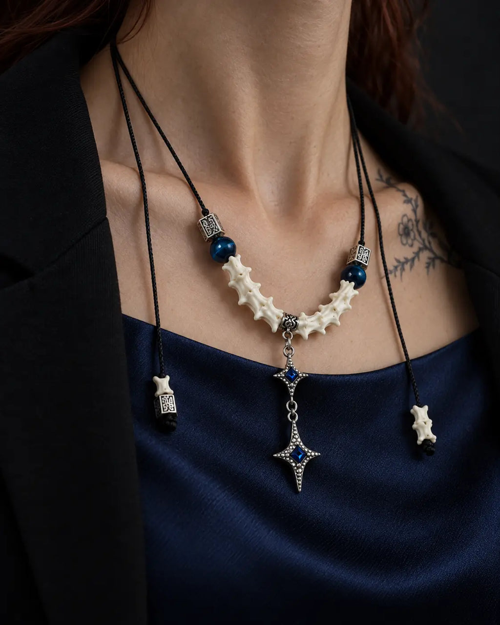 Angled close-up of the Azure Twin Star snake bone necklace showing white vertebrae and two hanging stars