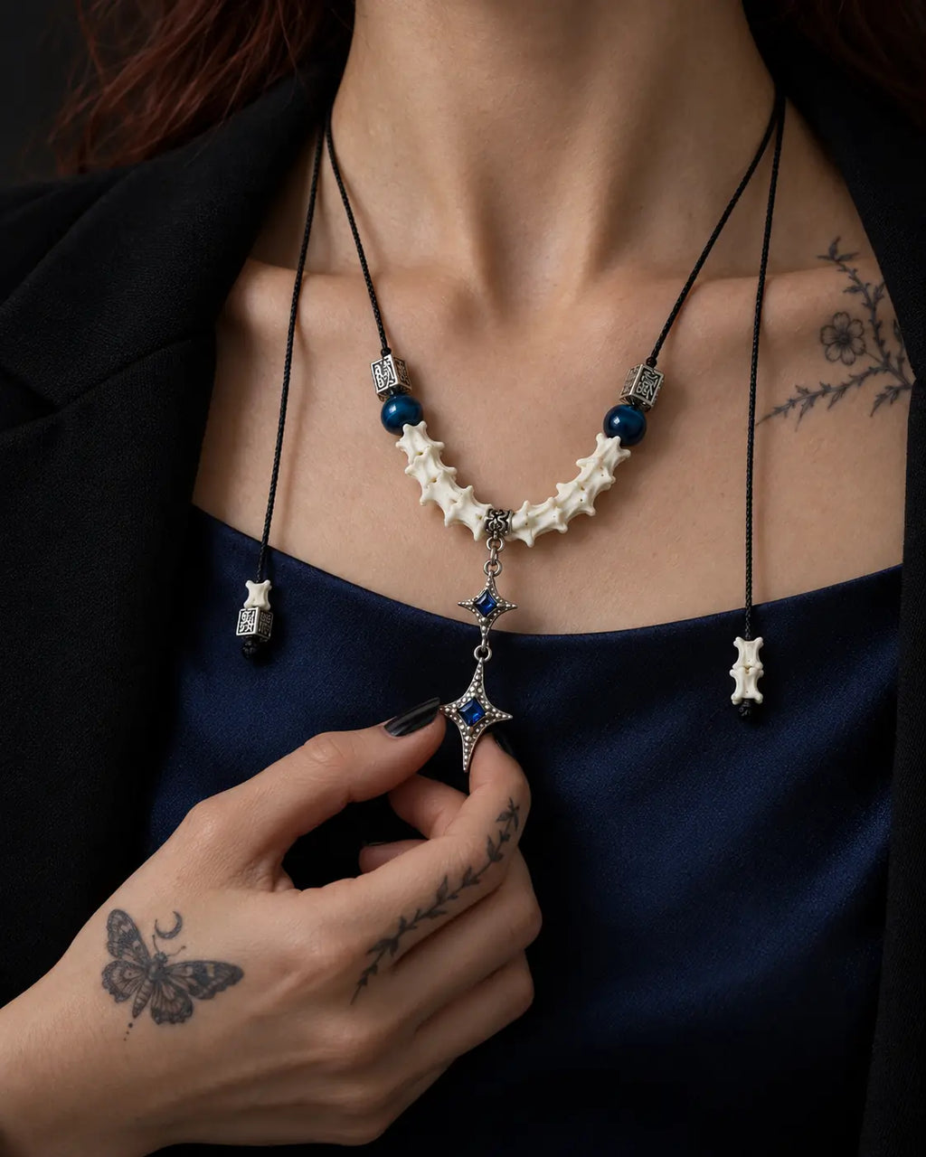 Azure Twin Star snake bone necklace worn at the chest with the lower star held between the fingers