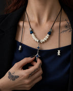 Azure Twin Star snake bone necklace worn at the chest with the lower star held between the fingers
