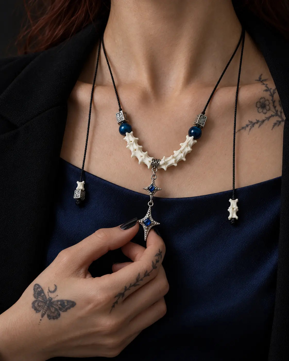 Azure Twin Star snake bone necklace worn at the chest with the lower star held between the fingers