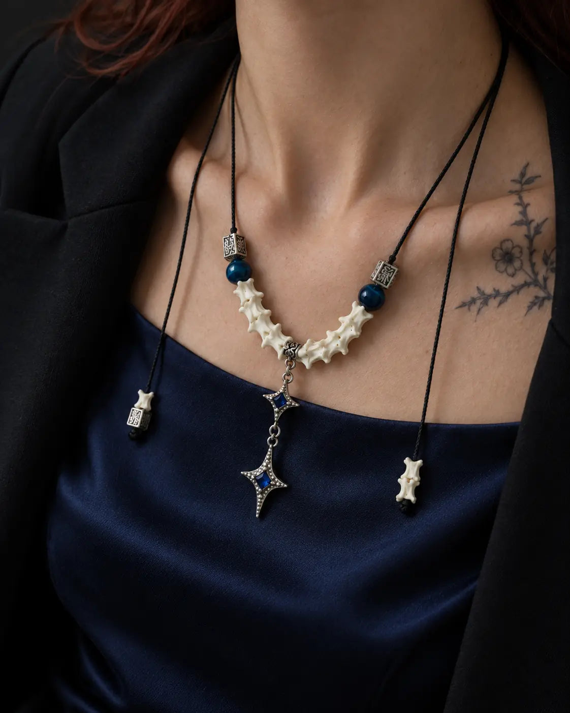 Close-up of the Azure Twin Star snake bone necklace worn over a draped blue satin neckline
