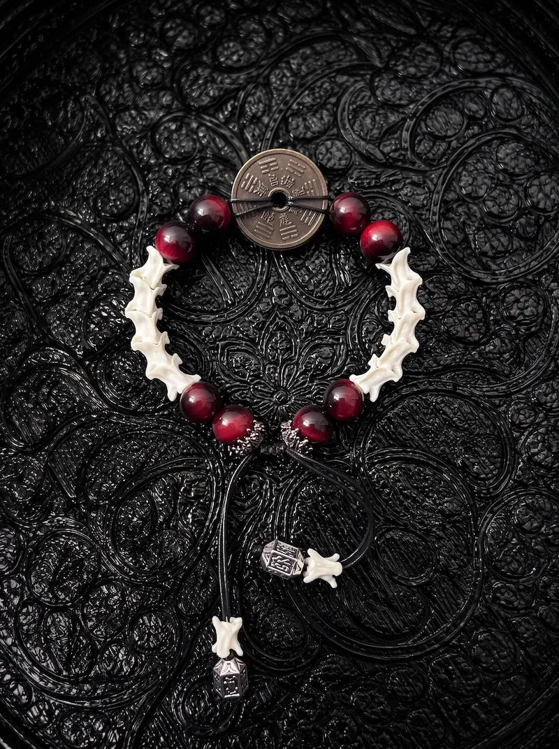 Bagua Coin snake bone bracelet with deep red beads, an antique-tone coin and bone- and metal-tipped black cords