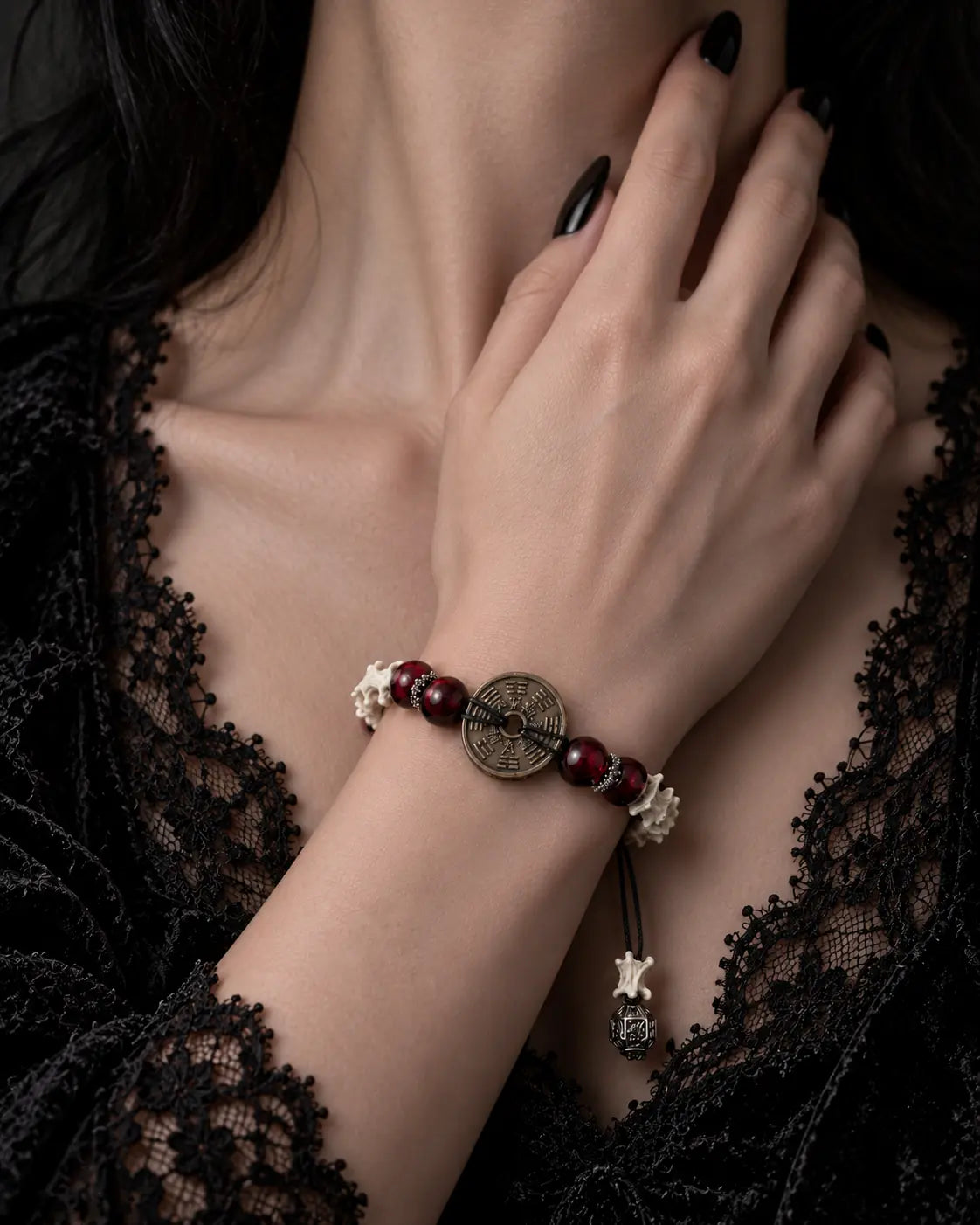 Bagua Coin snake bone bracelet worn with the hand near the neck above a black lace neckline, showing the engraved coin