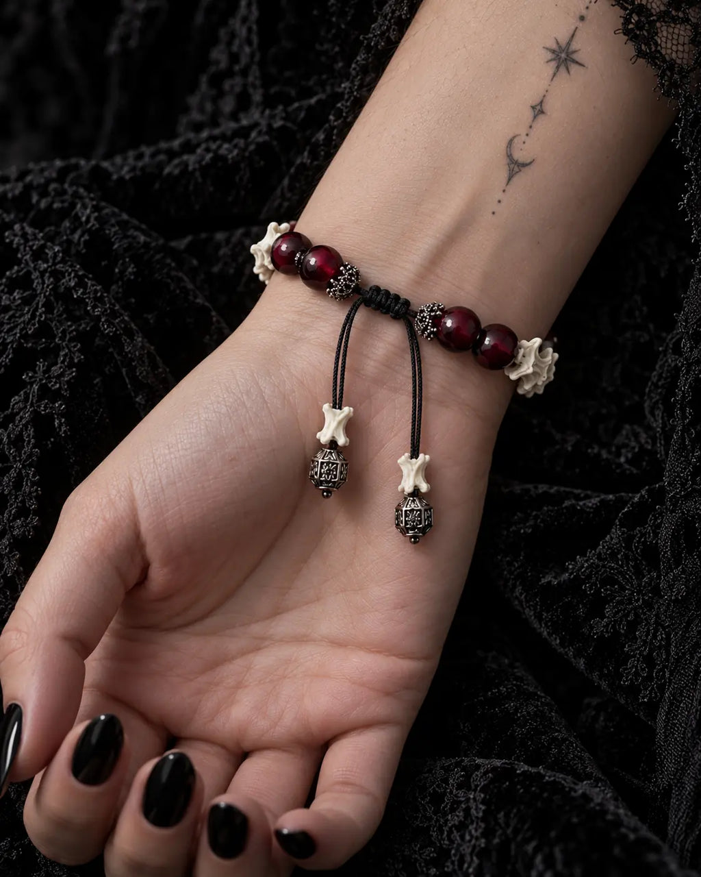 Palm-up view of the Bagua Coin snake bone bracelet showing its black sliding knot, red beads and cube-tipped cords