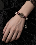 Bagua Coin snake bone bracelet on a hand resting on black velvet, with its round engraved coin facing upward