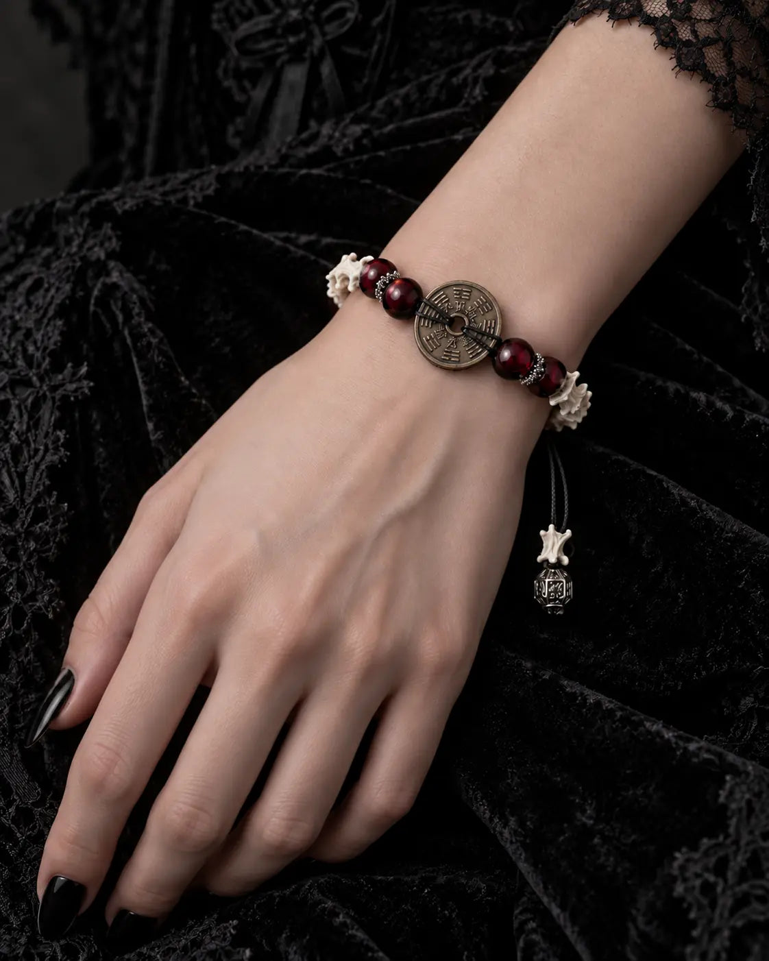 Bagua Coin snake bone bracelet on a hand resting on black velvet, with its round engraved coin facing upward