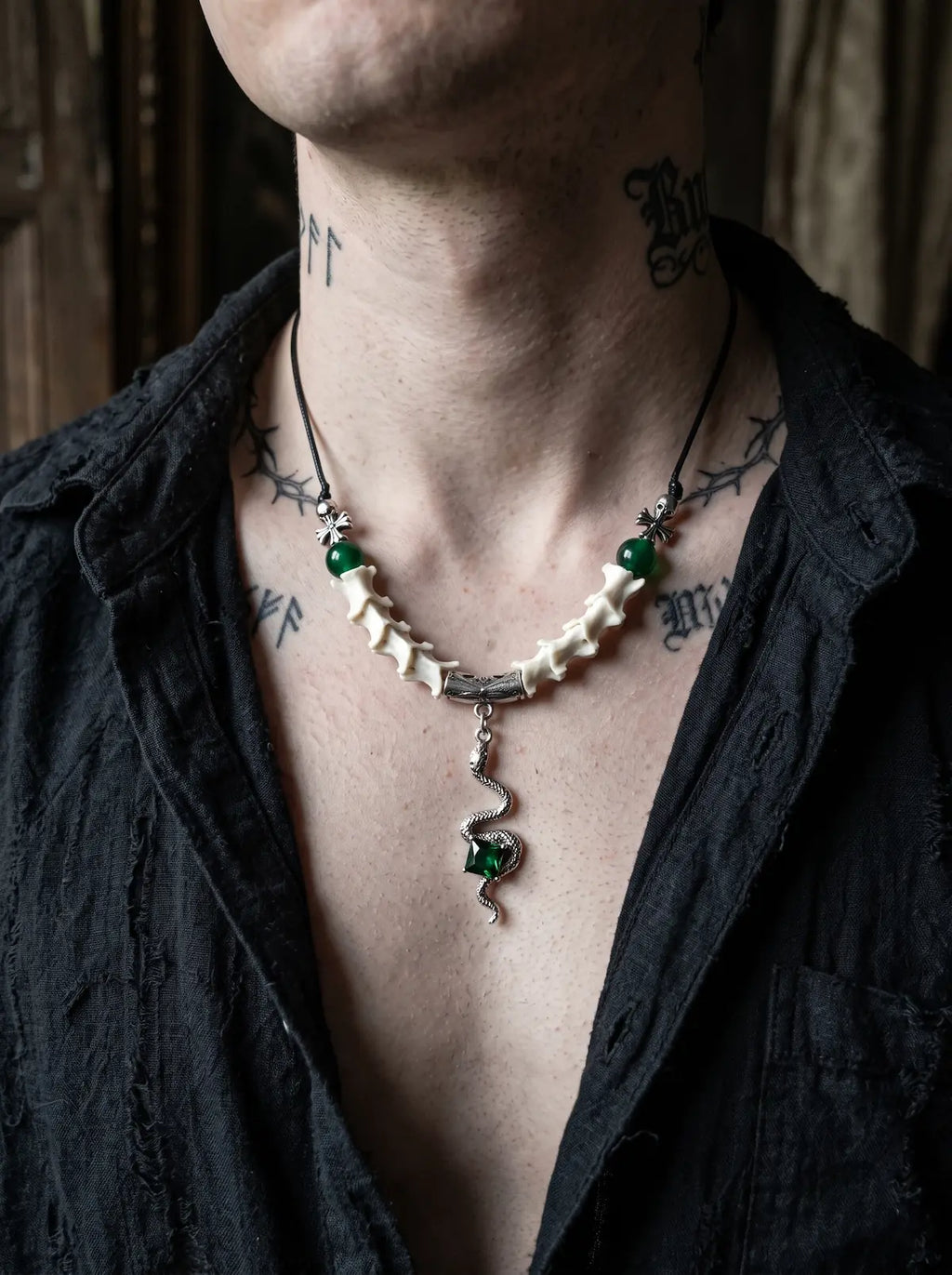 Basilisk Jewel Snake Bone Necklace, front view of green bead and white vertebrae necklace on an open dark shirt