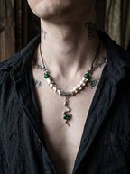 Basilisk Jewel Snake Bone Necklace, front view of green bead and white vertebrae necklace on an open dark shirt
