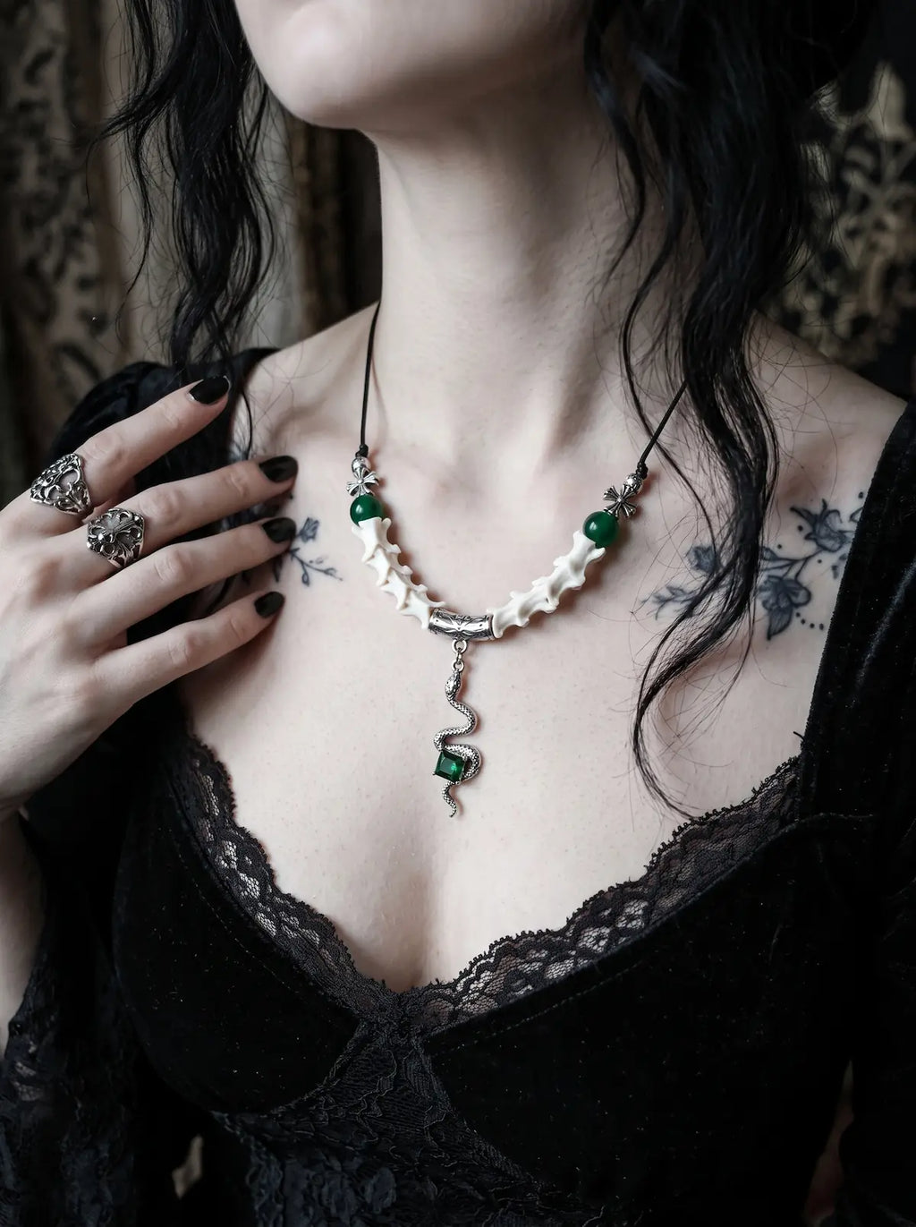 Basilisk Jewel Snake Bone Necklace, white vertebrae necklace with green bead accents on a tattooed collarbone