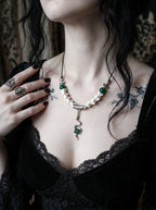 Basilisk Jewel Snake Bone Necklace, white vertebrae necklace with green bead accents on a tattooed collarbone