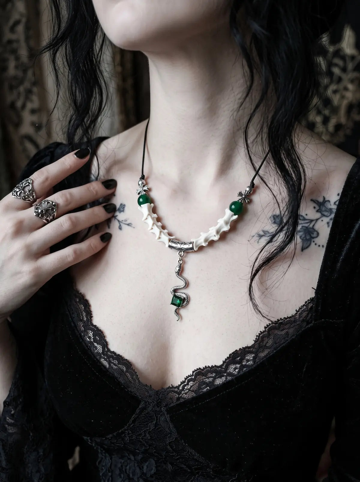 Basilisk Jewel Snake Bone Necklace, white vertebrae necklace with green bead accents on a tattooed collarbone