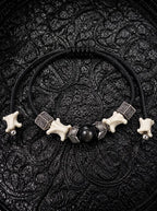 Black Orb snake bone bracelet with a glossy black center bead, leaf-shaped metal accents and adjustable black cords
