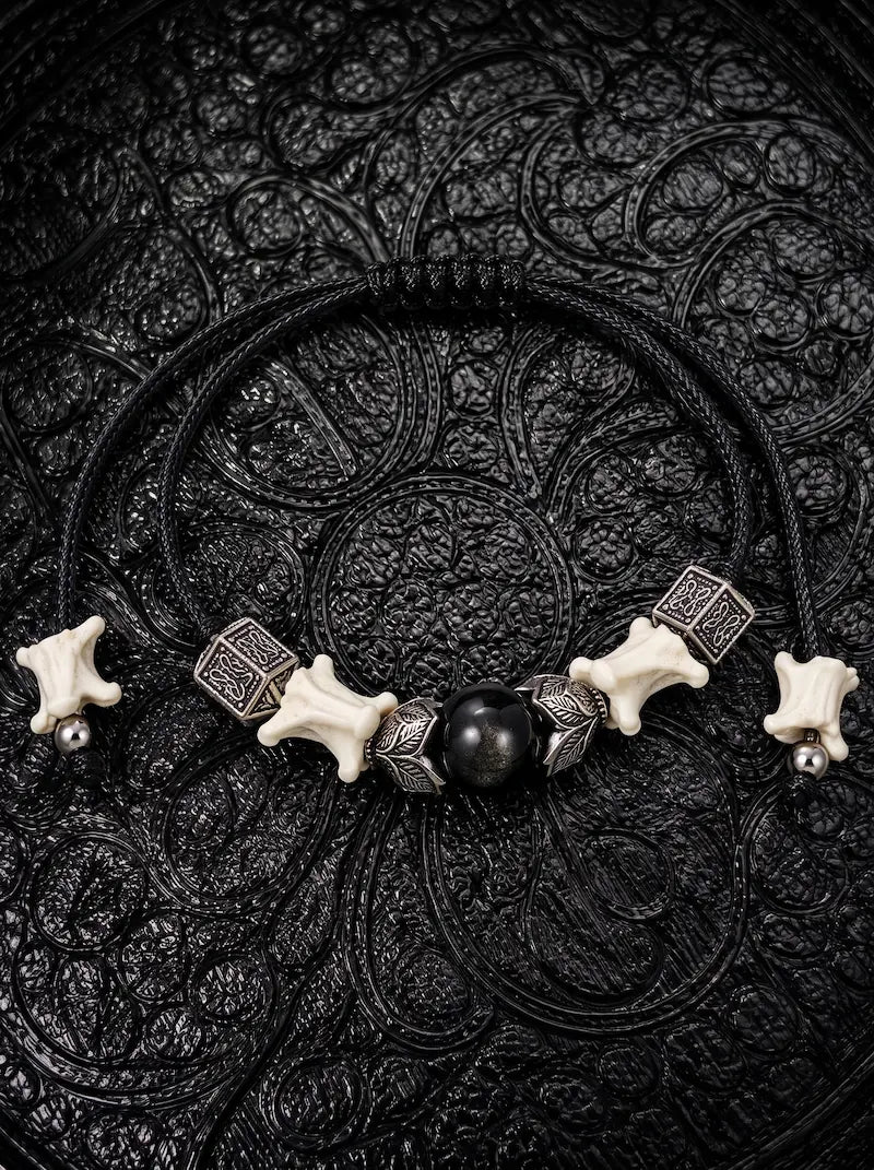 Black Orb snake bone bracelet with a glossy black center bead, leaf-shaped metal accents and adjustable black cords