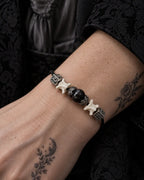Close-up of the Black Orb snake bone bracelet showing its glossy center bead and leaf-pattern metal caps on the wrist