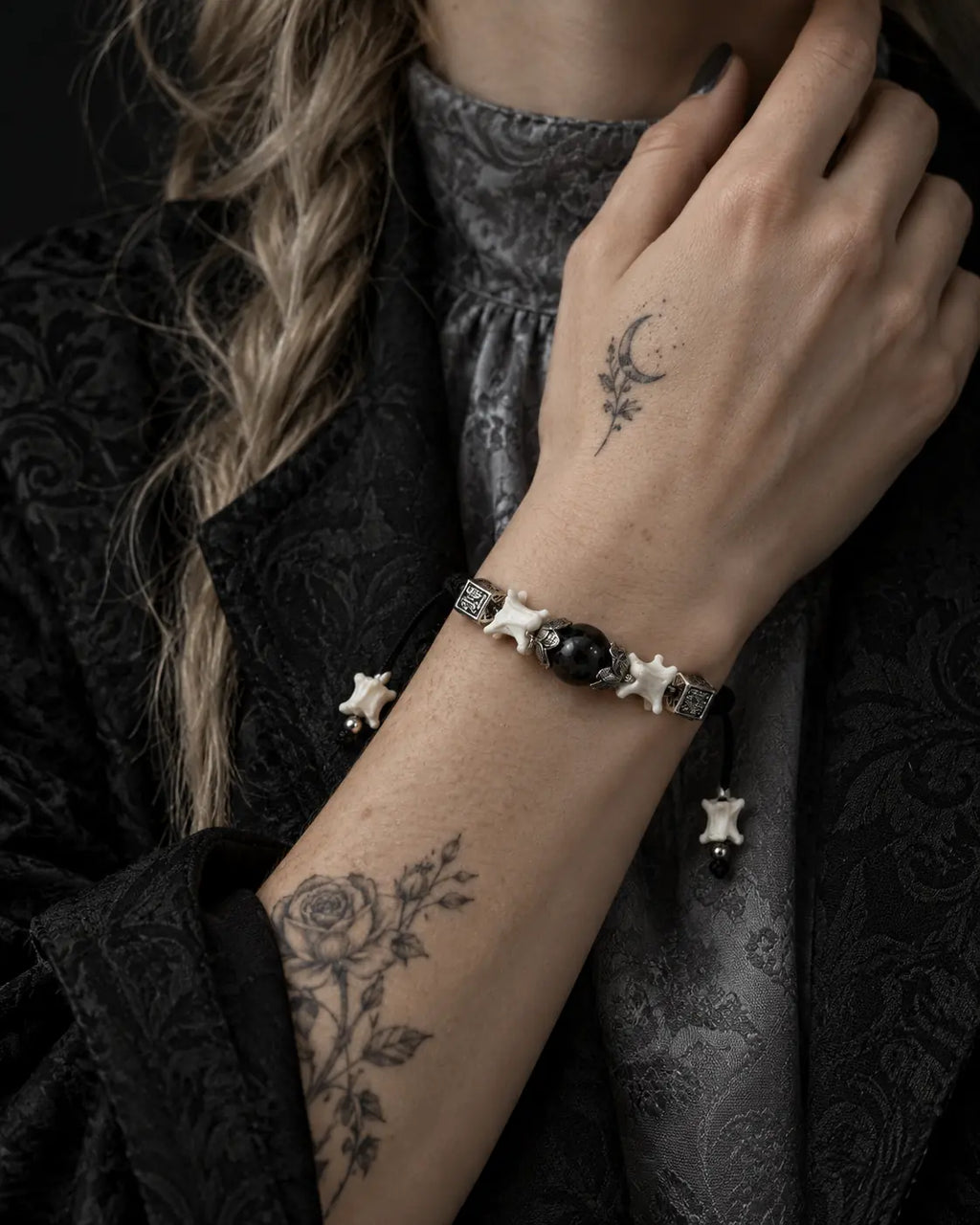 Black Orb snake bone bracelet shown on a raised wrist near the collar, with its black bead and square spacers visible
