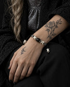 Black Orb snake bone bracelet on a hand resting on the thigh, showing the white vertebrae beside the black centerpiece