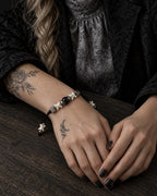 Black Orb snake bone bracelet worn with both hands resting on a wooden tabletop