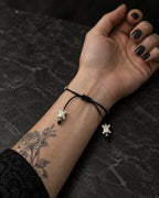 Palm-up view of the Black Orb snake bone bracelet showing its sliding knot and two bone-tipped black cords