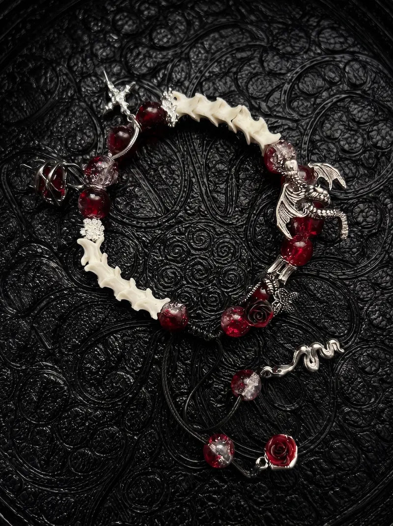 Blood Dragon snake bone bracelet with crimson beads, a silver-tone winged dragon, dark roses and dangling charms