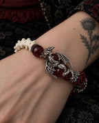Close-up of the Blood Dragon snake bone bracelet showing a silver-tone dragon curled around a deep red bead