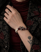 Blood Dragon snake bone bracelet worn with the hand at the lapel of a floral jacket over burgundy clothing