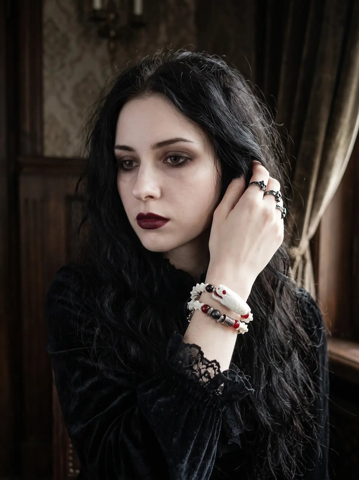 Bloodgaze Snake Bone Bracelet, preserved snake head and pale bone bracelet worn on a wrist near dark hair