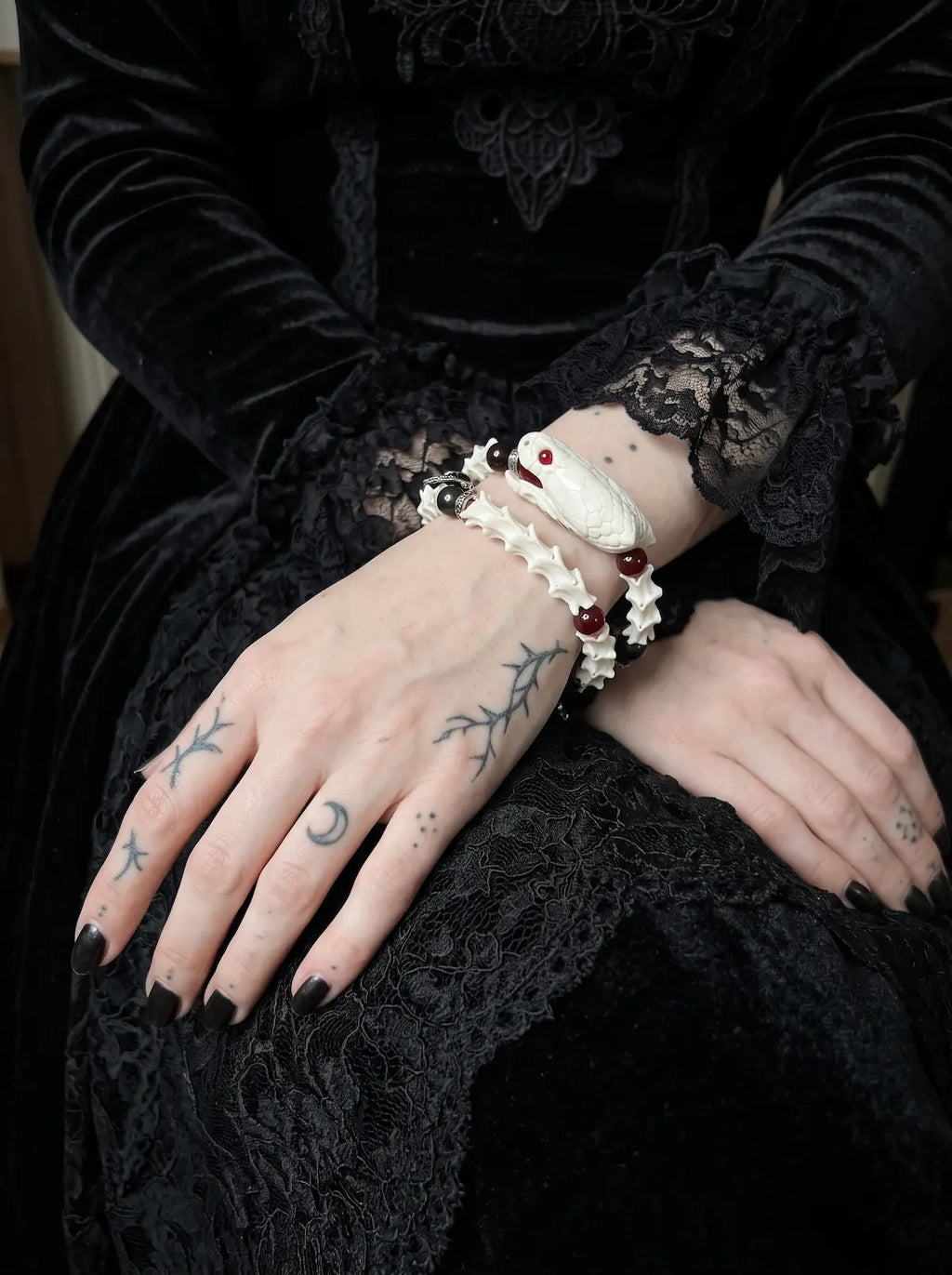 Bloodgaze Snake Bone Bracelet, wrist detail showing red beads and white snake bone beneath a black sleeve