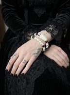 Bloodgaze Snake Bone Bracelet, wrist detail showing red beads and white snake bone beneath a black sleeve