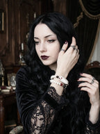 Bloodgaze Snake Bone Bracelet, snake head bracelet with red accents worn on a wrist in a seated gothic portrait