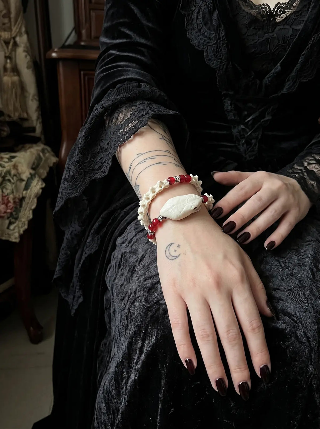 Bloodlance Snake Bone Bracelet, white snake head and red bead bracelet worn on the wrist over a black sleeve
