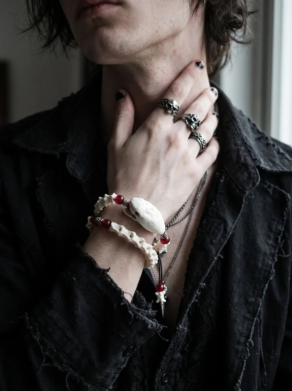 Bloodlance Snake Bone Bracelet, red accented snake bone bracelet on the wrist while the model touches the neck