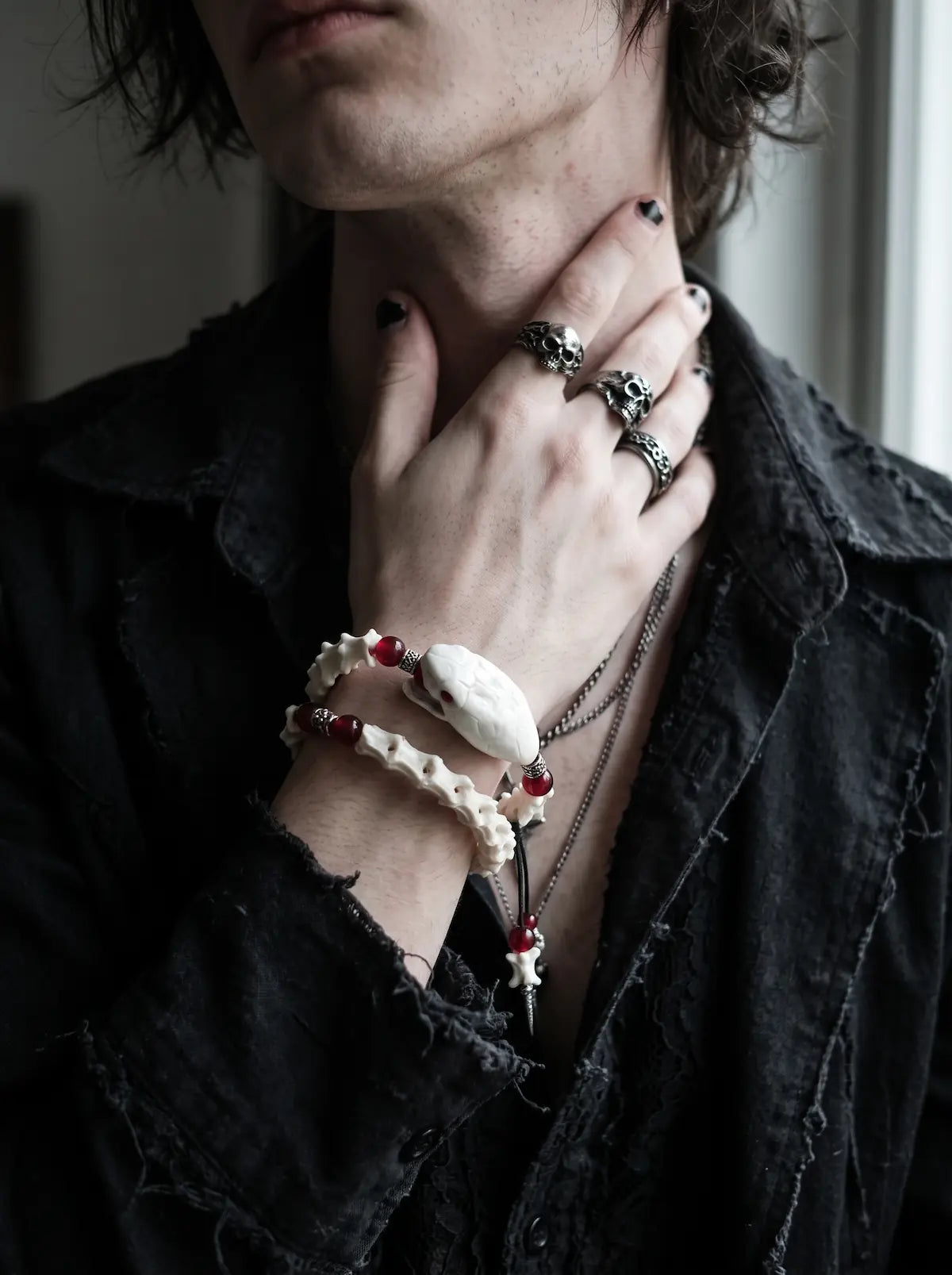 Bloodlance Snake Bone Bracelet, red accented snake bone bracelet on the wrist while the model touches the neck