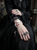 Bloodlance Snake Bone Bracelet, close wrist view of preserved pale snake head and red beads with dangling charms
